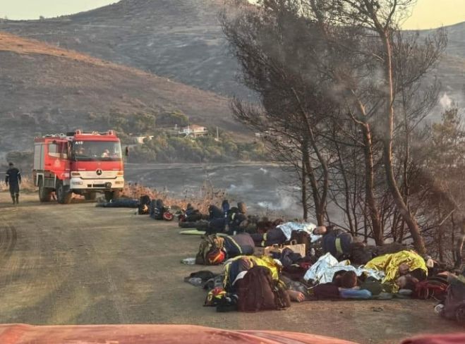 Εξαντλημένοι πυροσβέστες ξαπλώνουν στο χώμα για να ξεκουραστούν στην Κερατέα